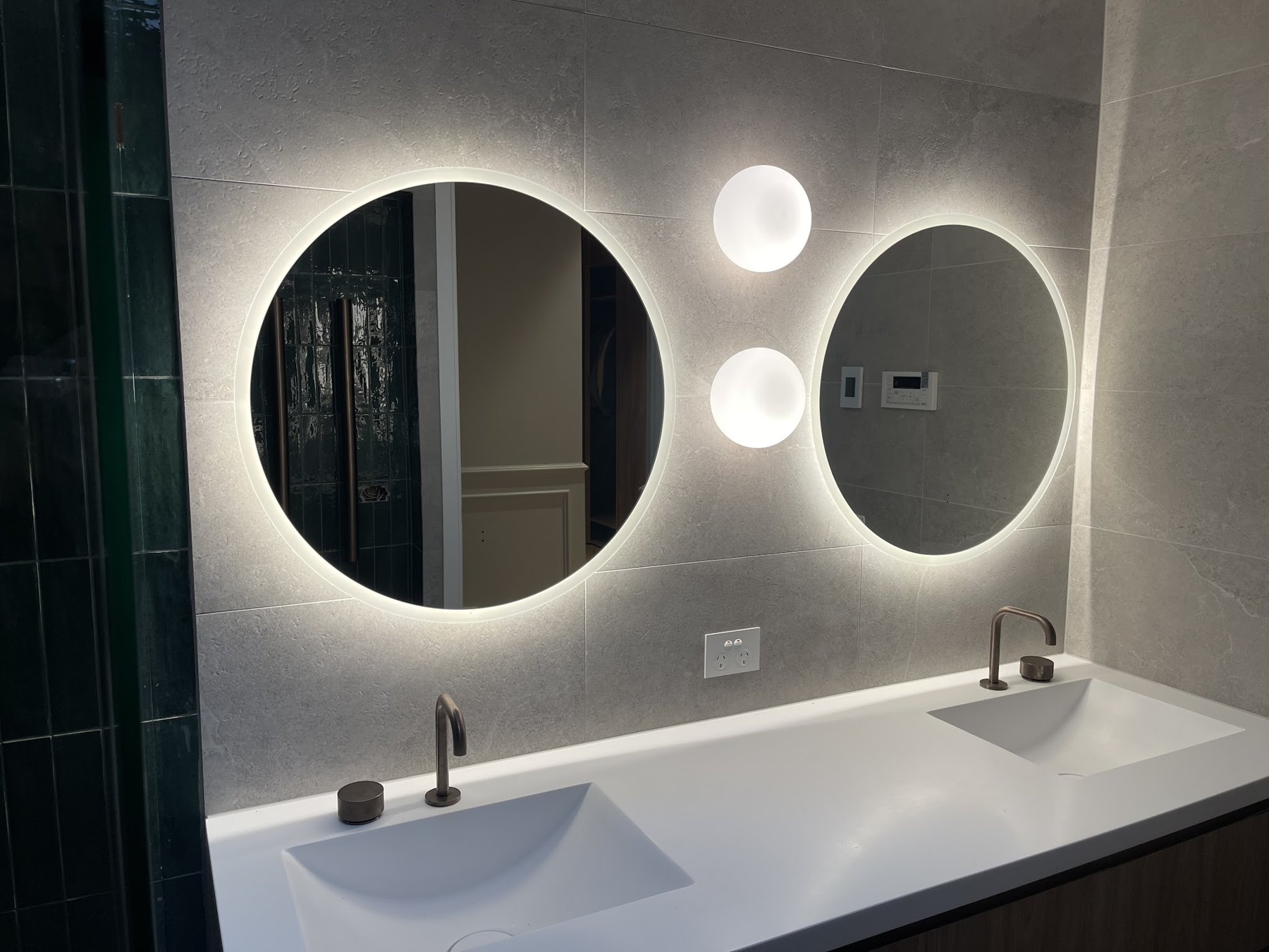 Double vanity with two round backlit mirrors, wall lights and a power point